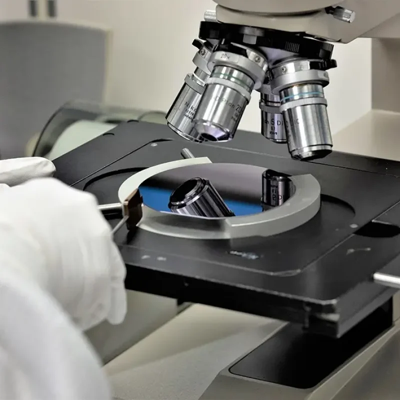 person in a clean suit in a lab using a microscope