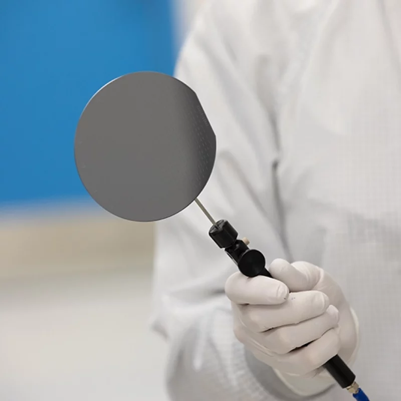 person in a clean suit in a lab carefully handling an epitaxial wafer