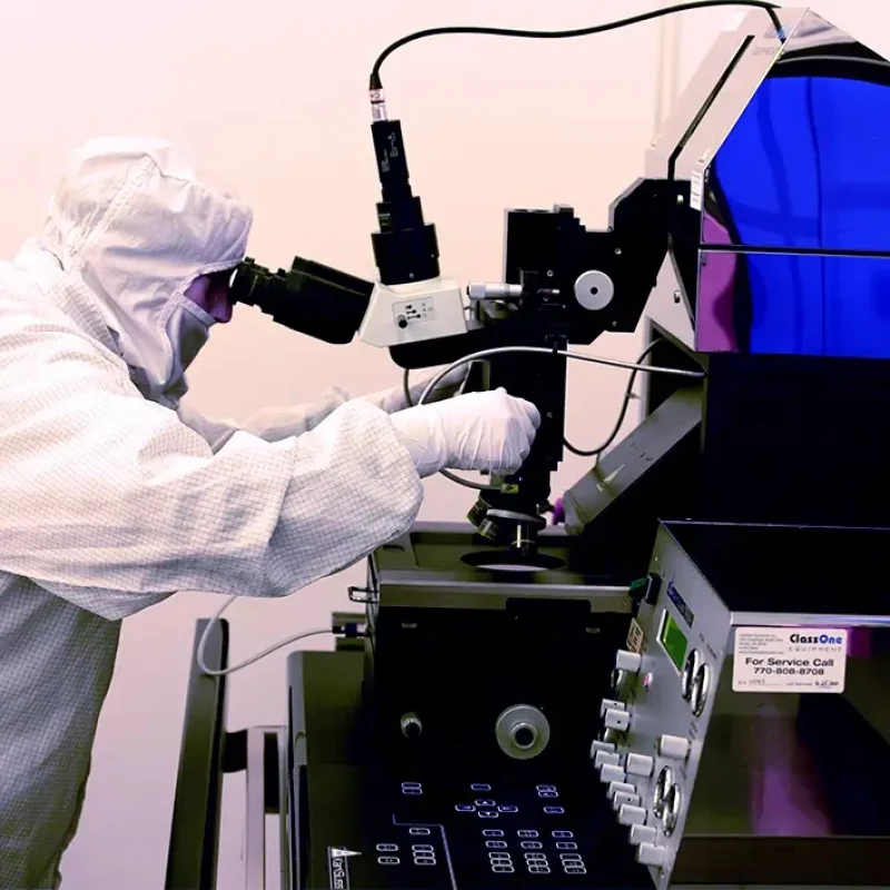 person in a clean suit in a lab using machinery