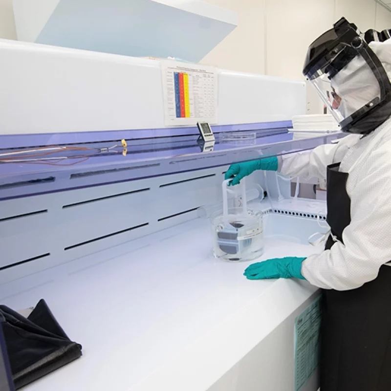 person in a clean suit in a lab carefully handling an epitaxial wafer
